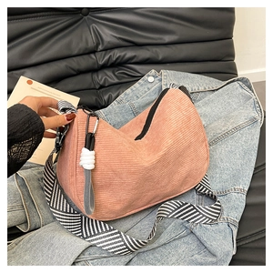 Close-up of pink corduroy half-moon bag featuring striped strap and woven zipper puller