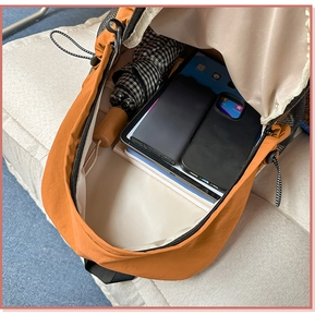 Interior view of orange nylon backpack showing large capacity for books and tablet