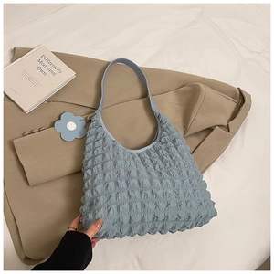 Close-up of light blue pleated hobo bag with textured bubble fabric and floral charm