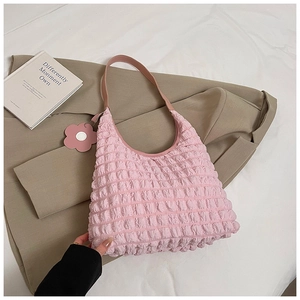 Detailed macro view of pink pleated texture with a floral pendant on a soft tote bag