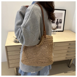 Detail of woven straw shoulder bag featuring intricate hollow mesh and leather strap