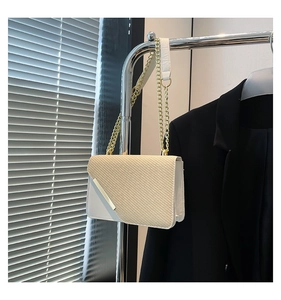 Detail of cream square bag showing textured flap and elegant gold chain strap