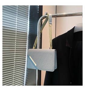 Close-up of light blue crossbody bag with denim texture and gold metal trim on the flap