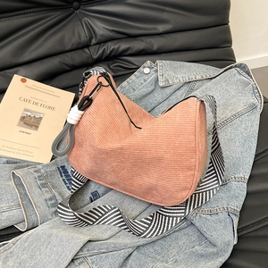 Pink corduroy crescent shoulder bag with a stylish black and white striped wide strap