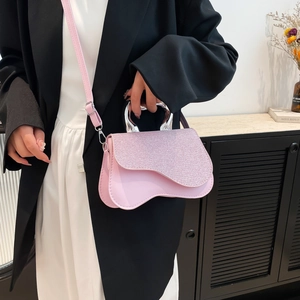 Pink glitter handbag with wave design and silver metal handle worn by a model
