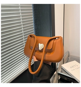 Detail of caramel shoulder bag featuring a silver heart buckle and padded top handle