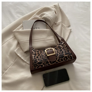 Détail du sac baguette léopard avec garniture en cuir brun et boucle dorée sur un blazer