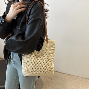 Cream crochet shoulder bag with brown leather strap worn by a model in a minimalist setting