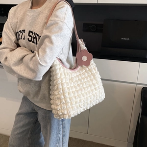 Stylish bubble texture tote bag in pink and white with floral charm on model's shoulder