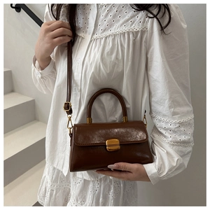 Detail of vintage brown leather handbag with gold buckle and adjustable shoulder strap