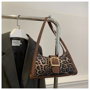 Détail d'un sac baguette léopard avec boucle dorée géante et lanière en cuir marron