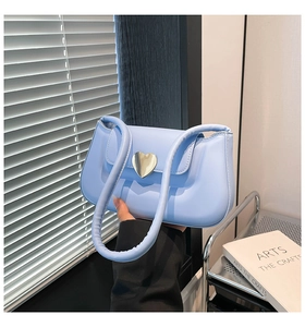 Detail of light blue faux leather bag with heart-shaped gold magnetic buckle closure