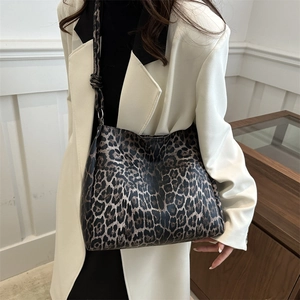 Stylish leopard print shoulder bag with knotted strap worn by a woman in white suit