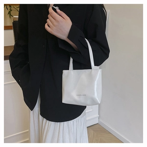 Dettaglio della piccola borsa tote bianca lucida con la scritta Fashion & Bags