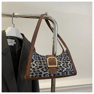 Détail de sac à bandoulière léopard avec bordure en cuir marron et boucle dorée