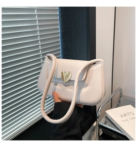Detailed close-up of cream leather shoulder bag featuring a gold heart-shaped metal clasp