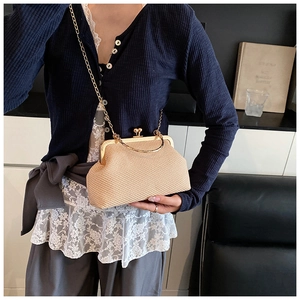 Detail of a beige woven clutch bag with gold metal clasp and chain on a female model