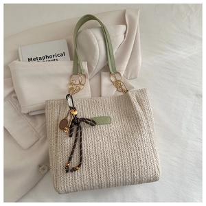Détail du cabas tissé avec bandoulière en cuir vert avocat et chaîne dorée