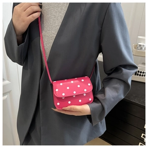 Close-up of fuchsia mini shoulder bag with white polka dot pattern on PU leather
