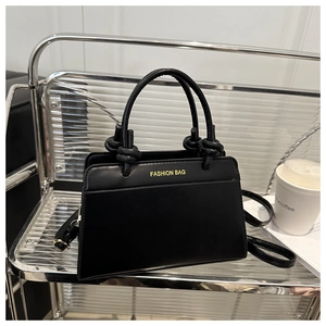 Detailed macro view of black faux leather tote with knotted handle and fashion logo
