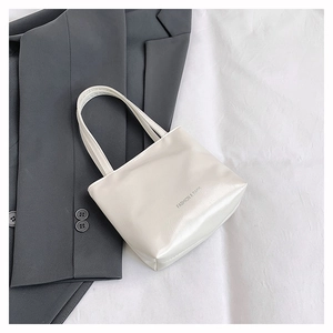 Dettaglio della borsa tote crema con testo Fashion & Bags su pelle sintetica lucida