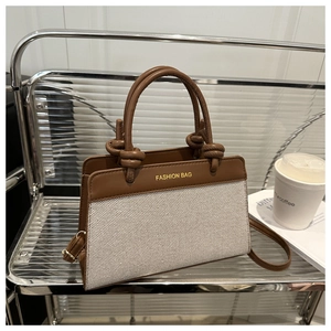 Detailed close-up of brown leather and beige canvas tote bag with fashion bag lettering