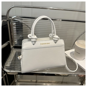 Detail of white leather saddle bag showing knot handle and gold metallic buckles