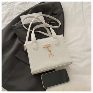 Détail du sac cabas blanc à motif litchi avec pendentif cerf doré et téléphone portable