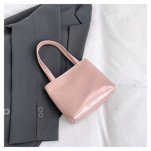 Dettaglio borsa tote rosa chiaro con trama in pelle e logo bianco su blazer grigio