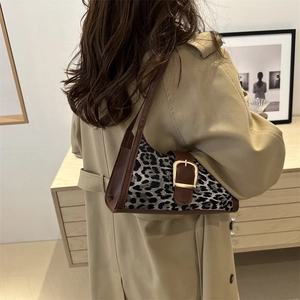 Sac baguette léopard avec bandoulière en cuir sur l'épaule d'un trench-coat beige