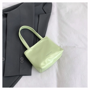 Dettaglio della borsa tote in pelle PU verde lime con stampa FASHION & BAGS su abito grigio