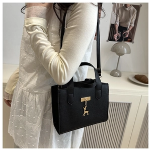 Détail du cabas en cuir grainé noir avec pendentif cerf doré et boucle en métal