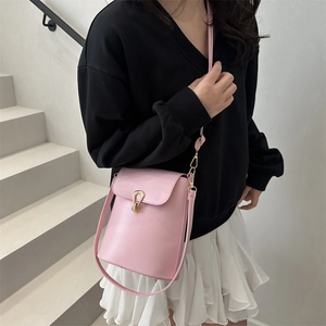 Sac à bandoulière rose avec fermoir en fer à cheval doré porté par un mannequin