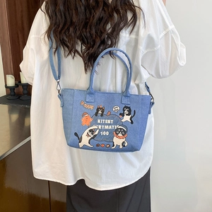 Borsa tote in denim blu con stampe cartoon carine e tracolla regolabile indossata dalla modella