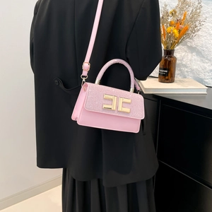 Pink luxury handbag with glitter flap and gold geometric clasp worn by a female model