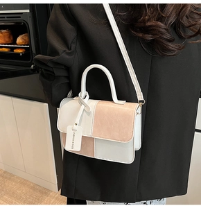 Detail of color-block crossbody bag featuring white and pink PU leather and fashion tag