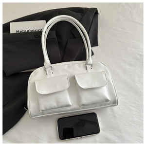 Detailed view of white dual-pocket shoulder bag next to a smartphone for size reference
