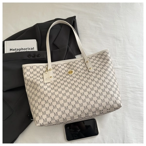 Detailed top view of large cream tote bag with monogram print and gold hardware