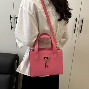 Sac fourre-tout rose avec pendentif cerf porté à l'épaule dans un style urbain chic