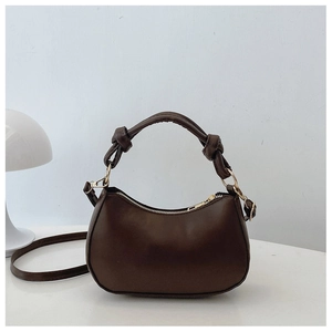 Detail of dark brown crescent bag showing knot handle and gold zipper hardware