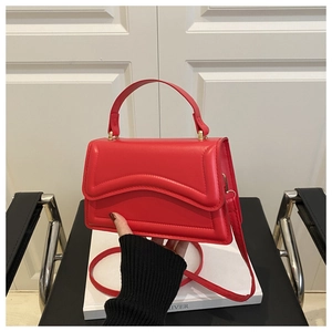 Detail of red square handbag with wave stitching and adjustable leather shoulder strap