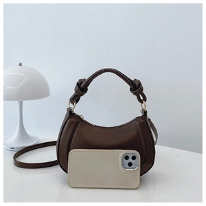 Detail view of dark brown crescent bag with knotted handle showing smartphone size comparison