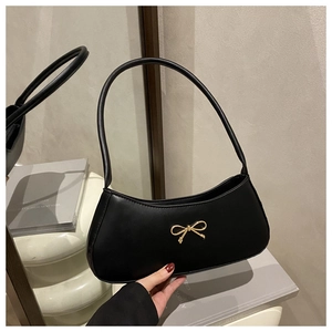 Detailed view of black hobo bag with an elegant golden metallic bow buckle decoration