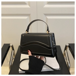 Detail view of black matte leather bag with wave stitching and gold metal buckle hardware