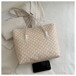 Detalle de bolso tote beige con estampado de monograma y gran capacidad interior