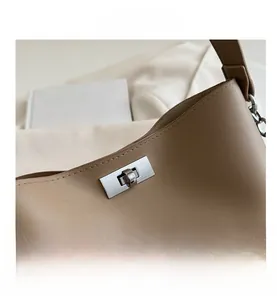Gros plan du fermoir rotatif argenté sur un sac seau en cuir marron de style élégant