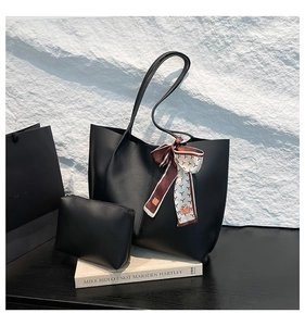 Minimalist black tote bag set with matching pouch and silk scarf detail on stone background