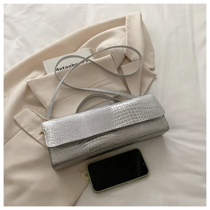 Detail of silver crocodile pattern crossbody bag showing texture and smartphone size reference