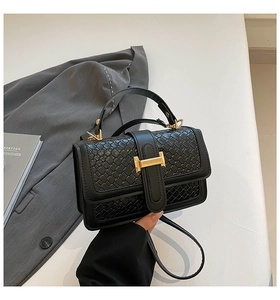 Close-up of black woven leather handbag with a gold H-lock on a textured blazer background