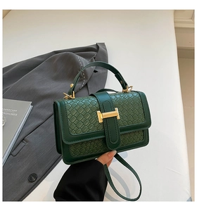 Detailed view of dark green woven leather bag with iconic golden H-shaped clasp